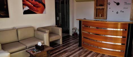 Una sala de estar con un sofá, una mesa de centro y un mostrador de recepción de madera.