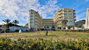 Hotel com vários andares e um pátio central, rodeado por vegetação e palmeiras.