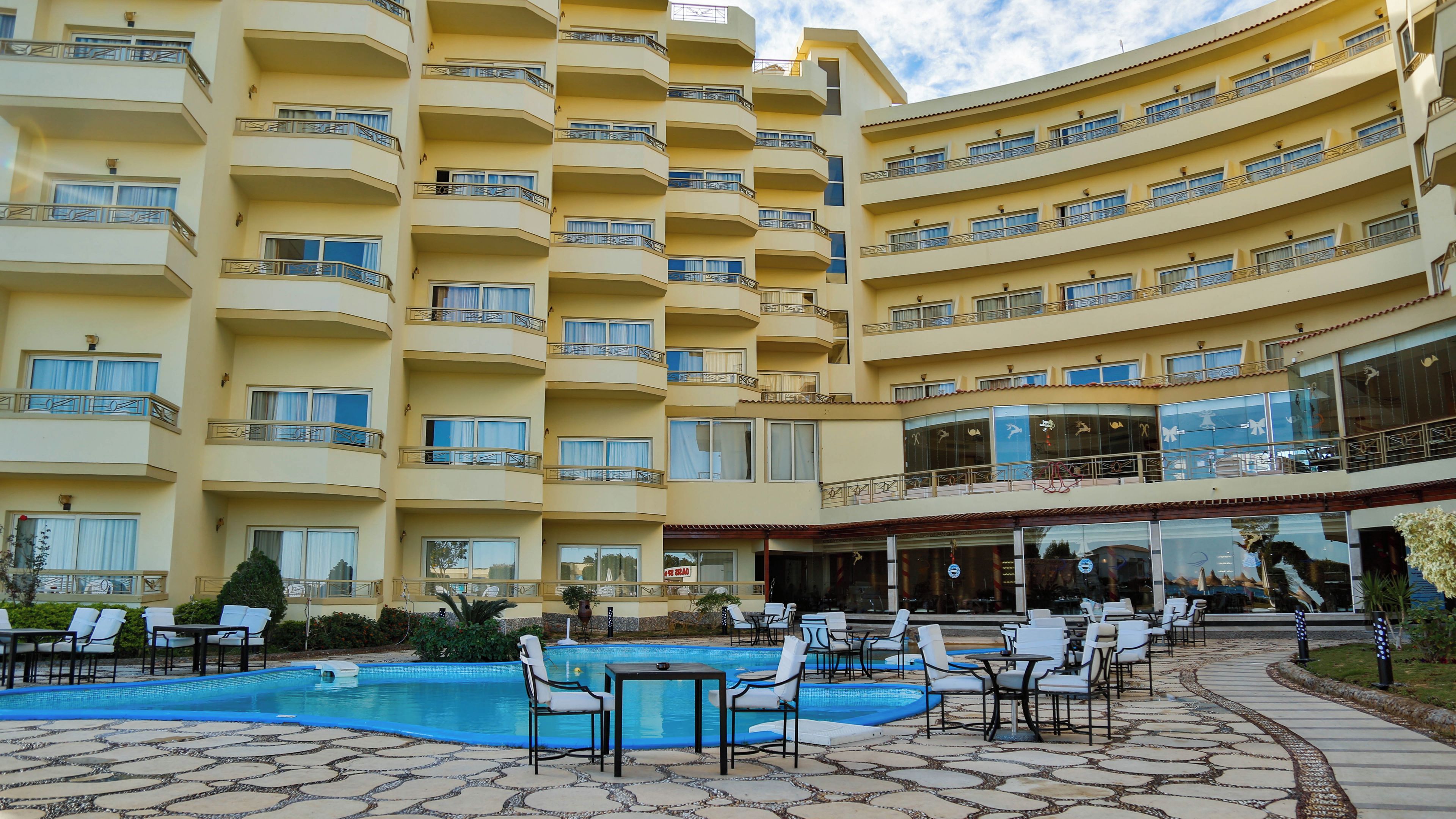 Un hôtel à plusieurs étages doté d’une piscine et d’un espace extérieur aménagé avec des sièges.
