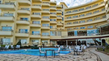 Um hotel com vários andares, piscina e área de estar ao ar livre.