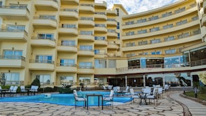 A multi-story hotel with a swimming pool and outdoor seating area.