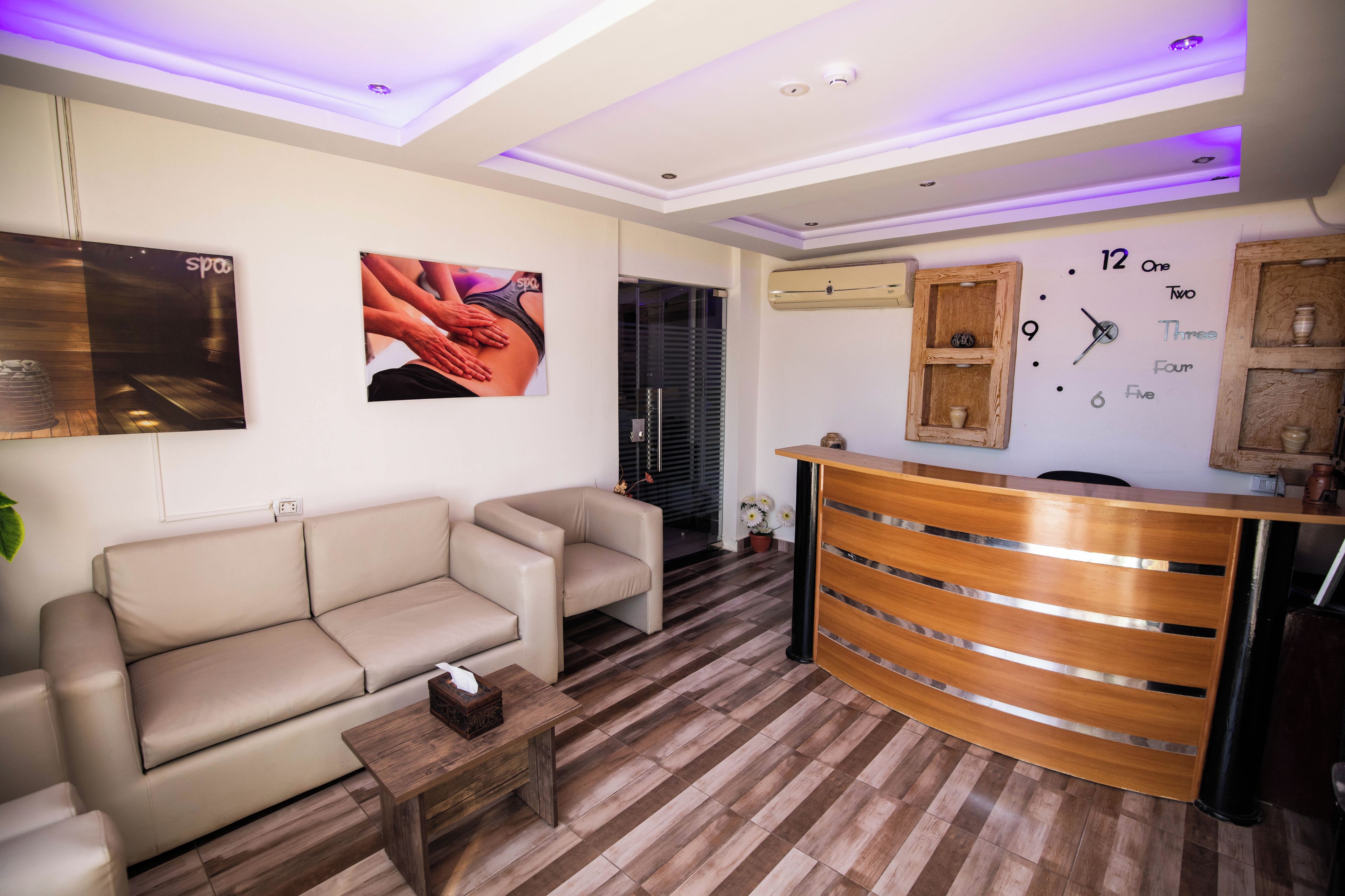 A modern reception area with a wooden reception desk, a beige sofa, and a small table.