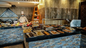 A buffet area with various food items and a chef preparing food. - Magic Beach Resort (Hurghada)