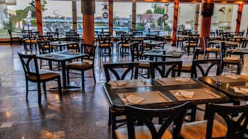 A restaurant with multiple tables and chairs, large windows, and a view of the outdoors.