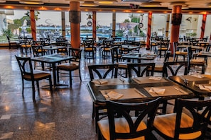 A restaurant with multiple tables and chairs, large windows, and a view of the outdoors. - Magic Beach Resort (Hurghada)