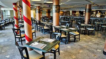 Un ristorante spazioso con diversi tavoli e sedie, caratterizzato da un design moderno con ampie colonne e pavimento lucido.