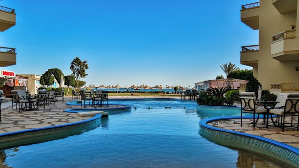 Un área de piscina con varias opciones de asientos y vista a la playa.
