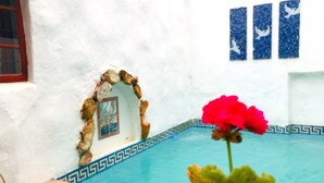 A pool with blue tiles and a white wall with a decorative archway. - Athenian Villa (Caledon)