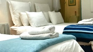 A hotel room with a bed, pillows, a blue blanket, and a white towel. - Athenian Villa (Caledon)