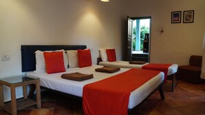 Une chambre d’hôtel avec deux lits, chacun agrémenté de draps rouges et blancs, une petite table et une vue sur l’extérieur.