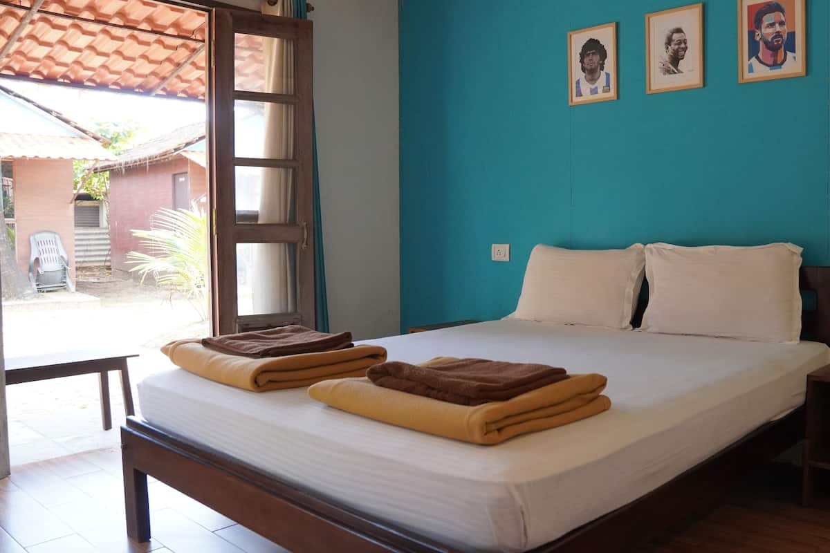 A bedroom with a bed, pillows, a nightstand, and a window.