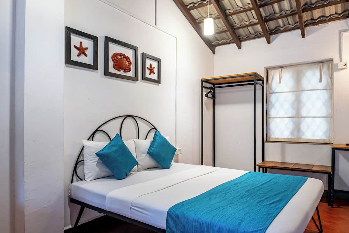 A single bed with a white mattress and blue bedding, a metal headboard, and a wall with three framed pictures of sea creatures.