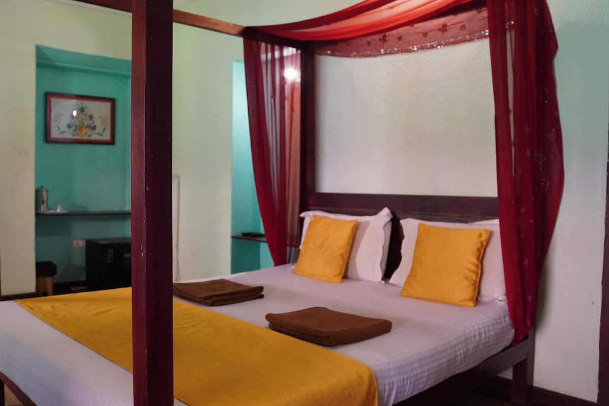 A four-poster bed with a canopy, two pillows, and a bedside table.