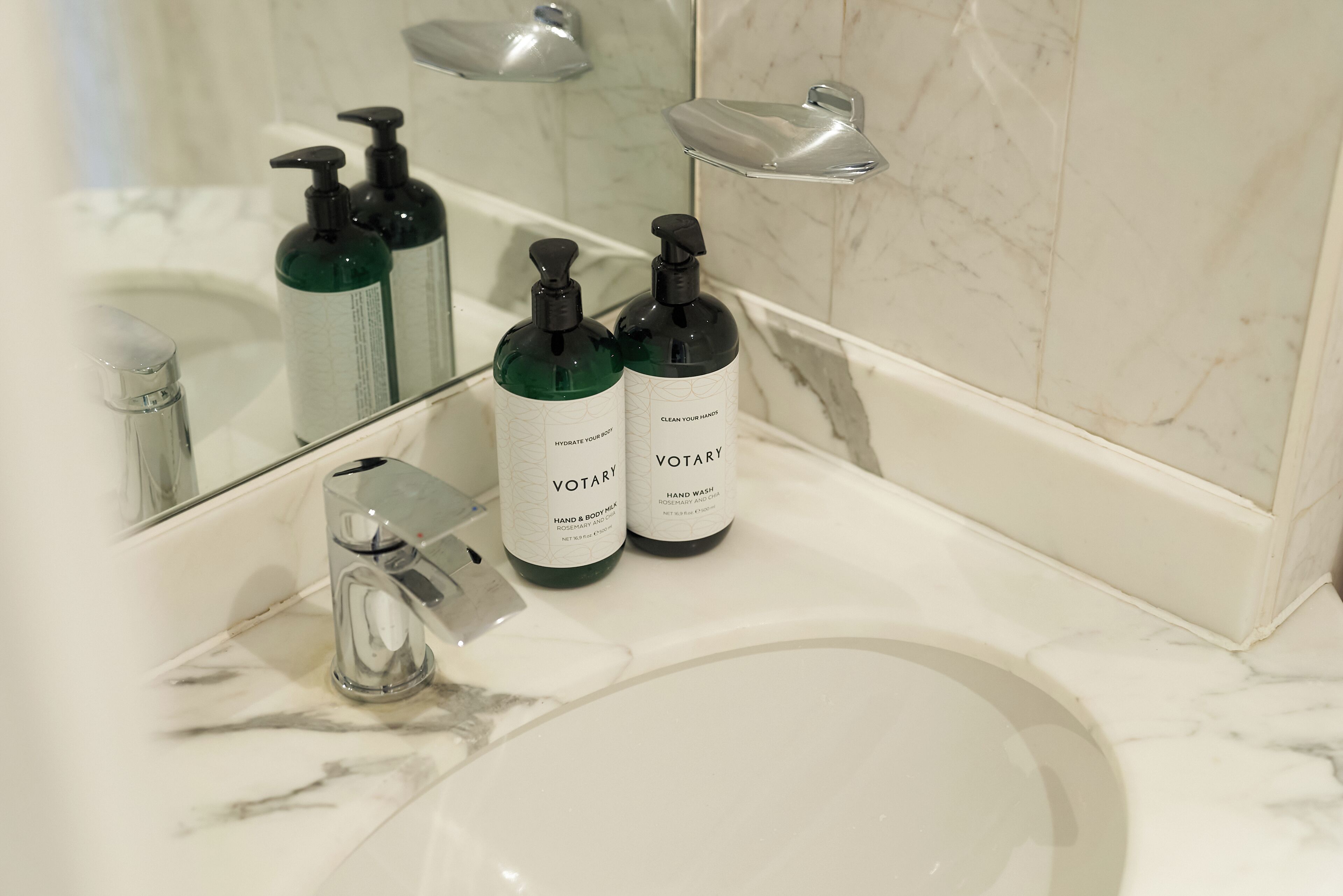 A bathroom with a white sink, two green hand soap bottles, and a mirror.