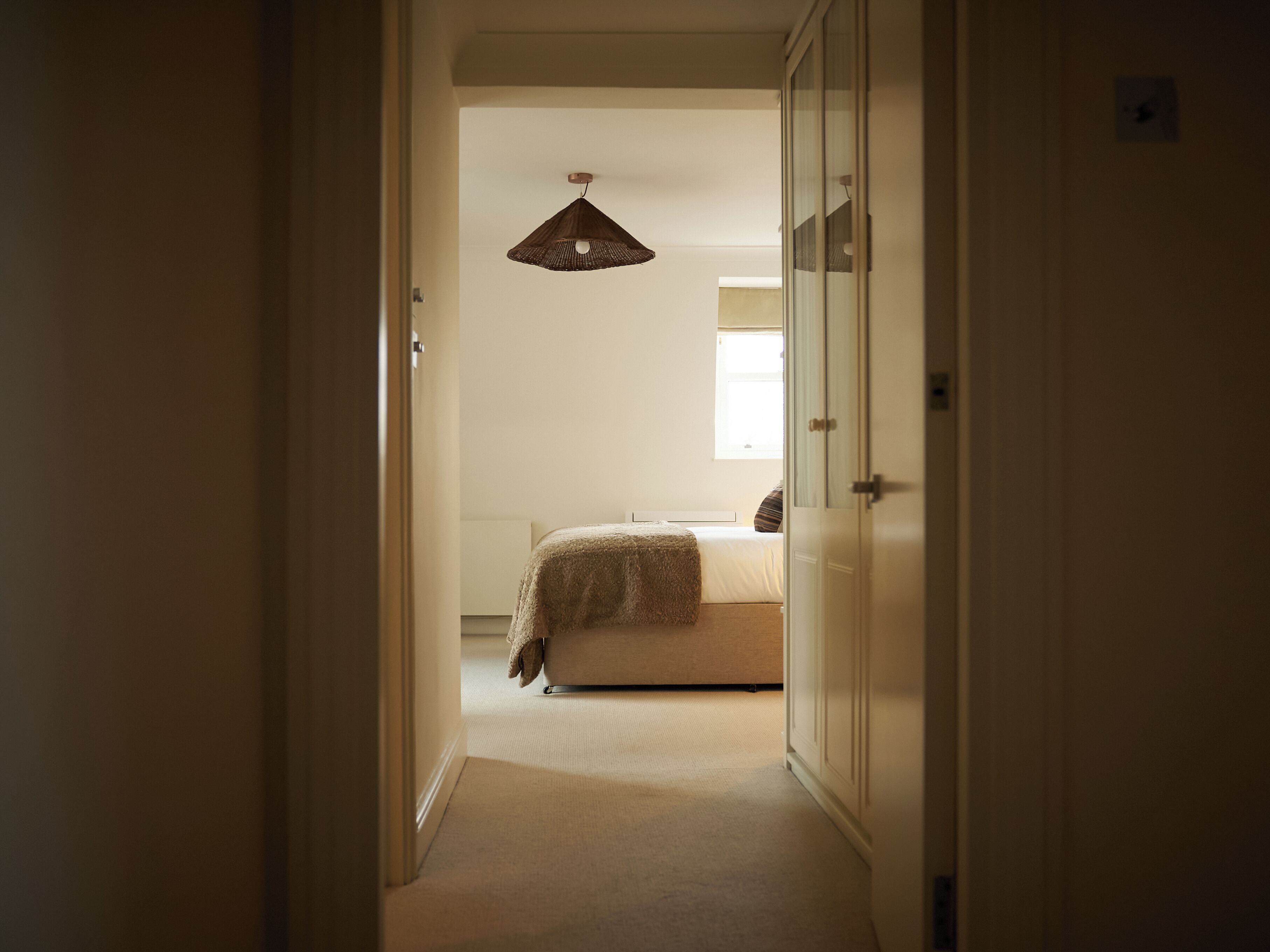 A bedroom with a bed, a hanging light fixture, and a wardrobe.