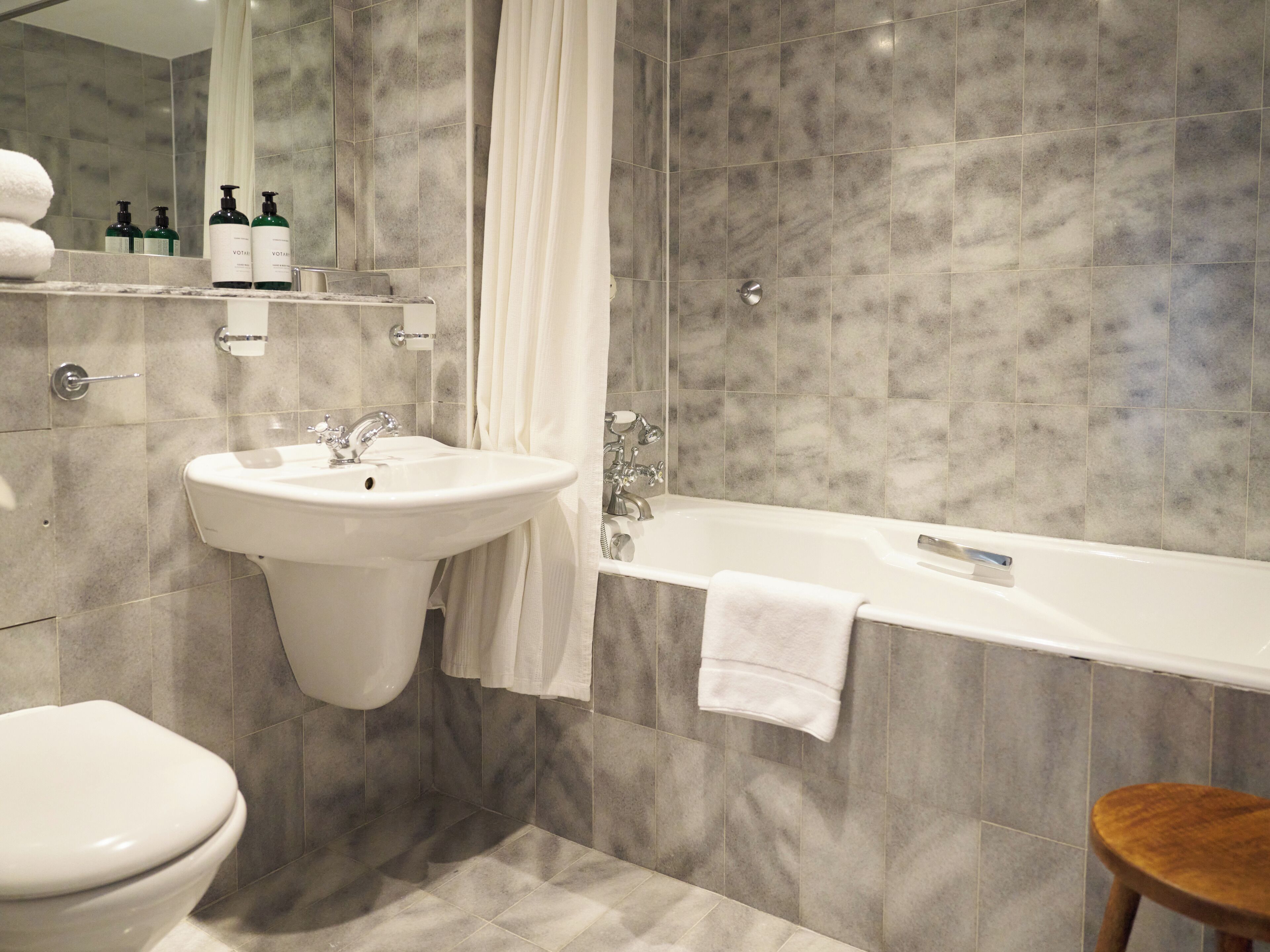 A modern bathroom with a white sink, a bathtub, and a toilet.