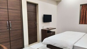 Een hotelkamer met een bed, een bureau, een televisie en een kledingkast.
