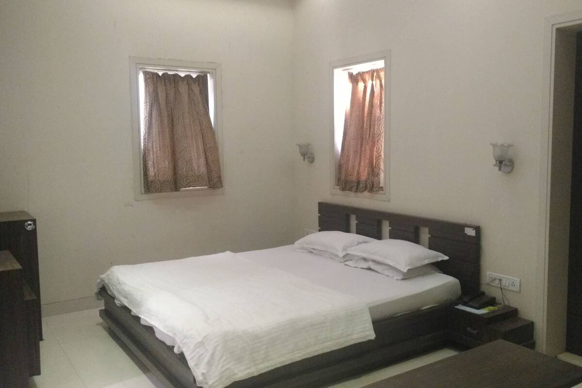 Una camera da letto con un letto, due finestre con tende, un comodino e un armadio.