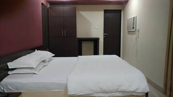 Una habitación de hotel con una cama, un armario, un escritorio y una puerta.
