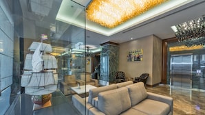 Um hall moderno com parede de vidro, modelo de navio, sofá e lustre.