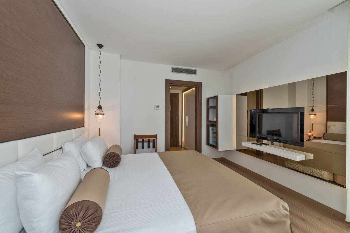Une chambre d’hôtel moderne dotée d’un grand lit, d’une télévision et d’un coin salon offrant une vue sur la ville.