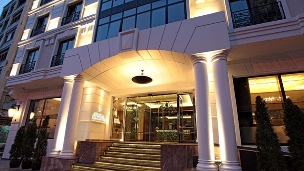 Entrada de hotel com um arco imponente, colunas grandes e fachada bem iluminada.