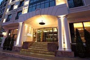 Una entrada de hotel con un arco imponente, amplias columnas y una fachada bien iluminada.