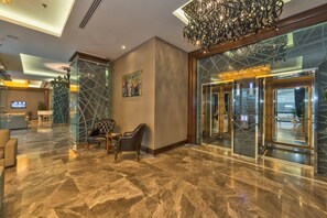 A lobby with marble flooring, leather seating, a chandelier, and a glass elevator. - Istanbul Dora Hotel (Istanbul)