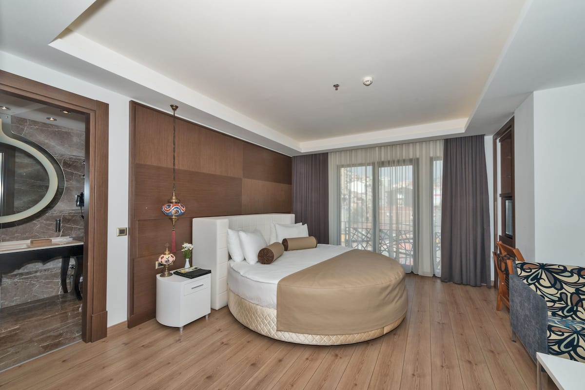Une chambre à coucher moderne avec un lit rond, une table de chevet, un miroir et une vue sur la ville.