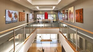 A spacious atrium with a glass railing, artwork on the walls, and a wooden floor. - Quest Albury On Townsend (Albury)
