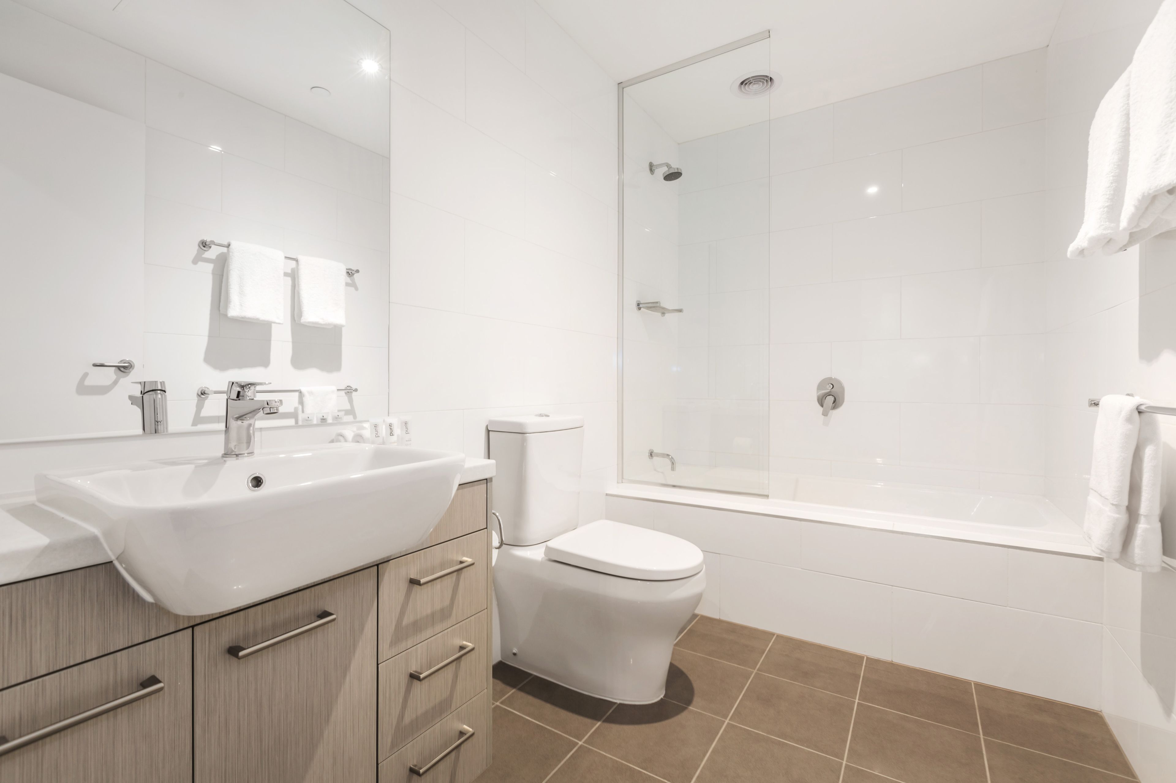 A modern bathroom with a large white sink, a toilet, and a glass-enclosed shower.