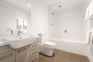 A modern bathroom with a large white sink, a toilet, and a glass-enclosed shower. - Quest Albury On Townsend (Albury)