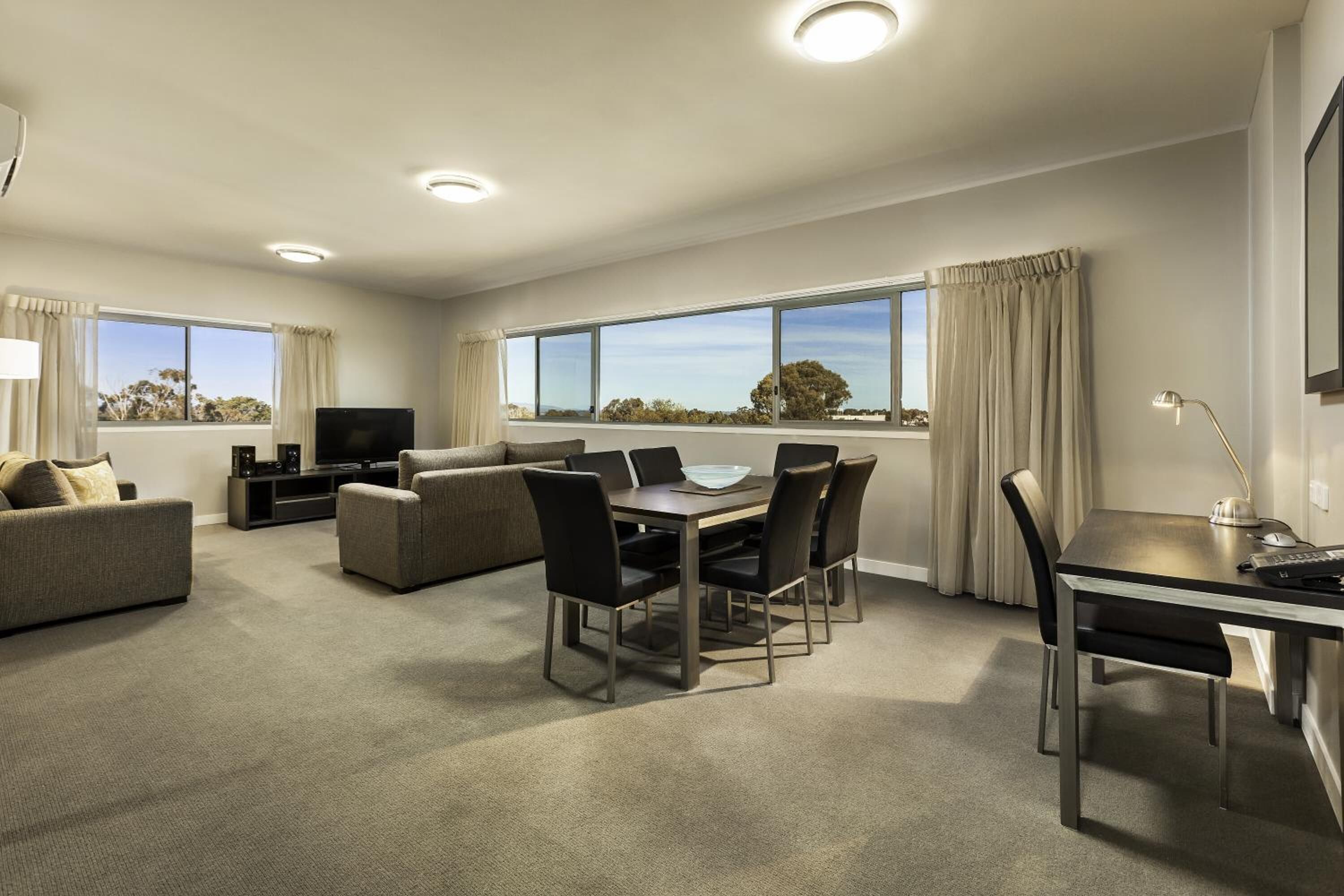 Una sala moderna con sofá, televisión y comedor con sillas y una mesa.