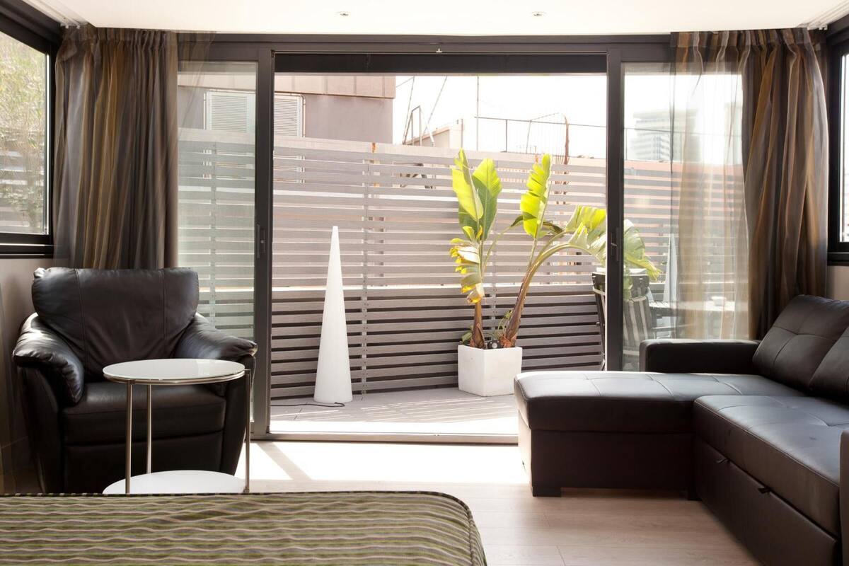 A modern living room with a sofa, a chair, a small table, and a potted plant.