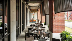 An outdoor seating area with tables and chairs, a brick wall, and a sign for the Epicurean Theatre.