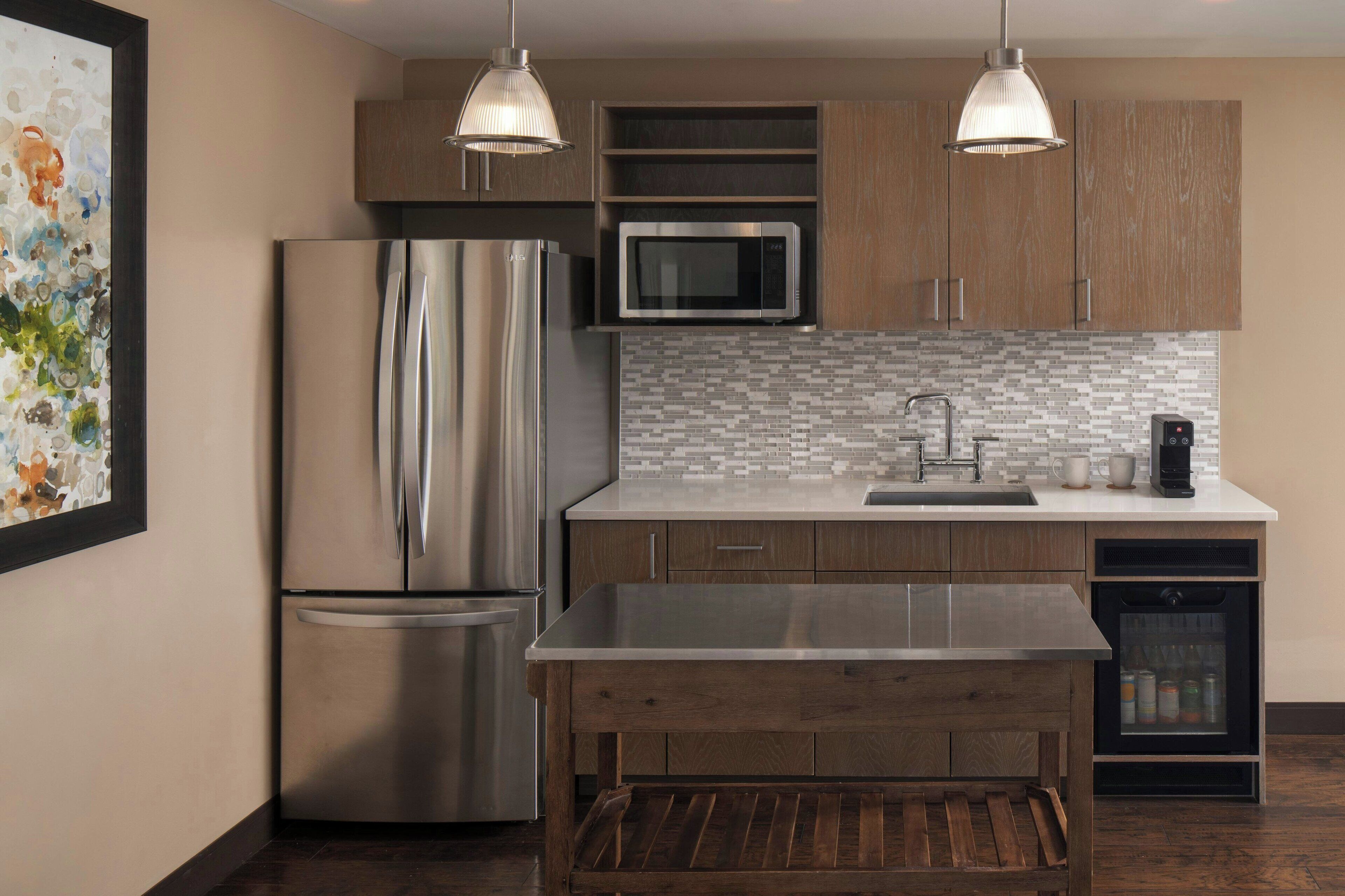 A modern kitchen with stainless steel appliances, wooden cabinets, and a tiled backsplash.
