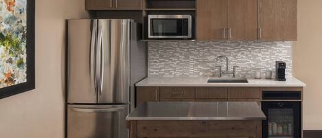 A modern kitchen with stainless steel appliances, wooden cabinets, and a tiled backsplash.