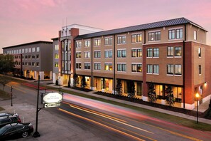 Een meerhoog hotel met een modern design, met een bord voor een steakhouse, valetparking en een goed verlichte entree.