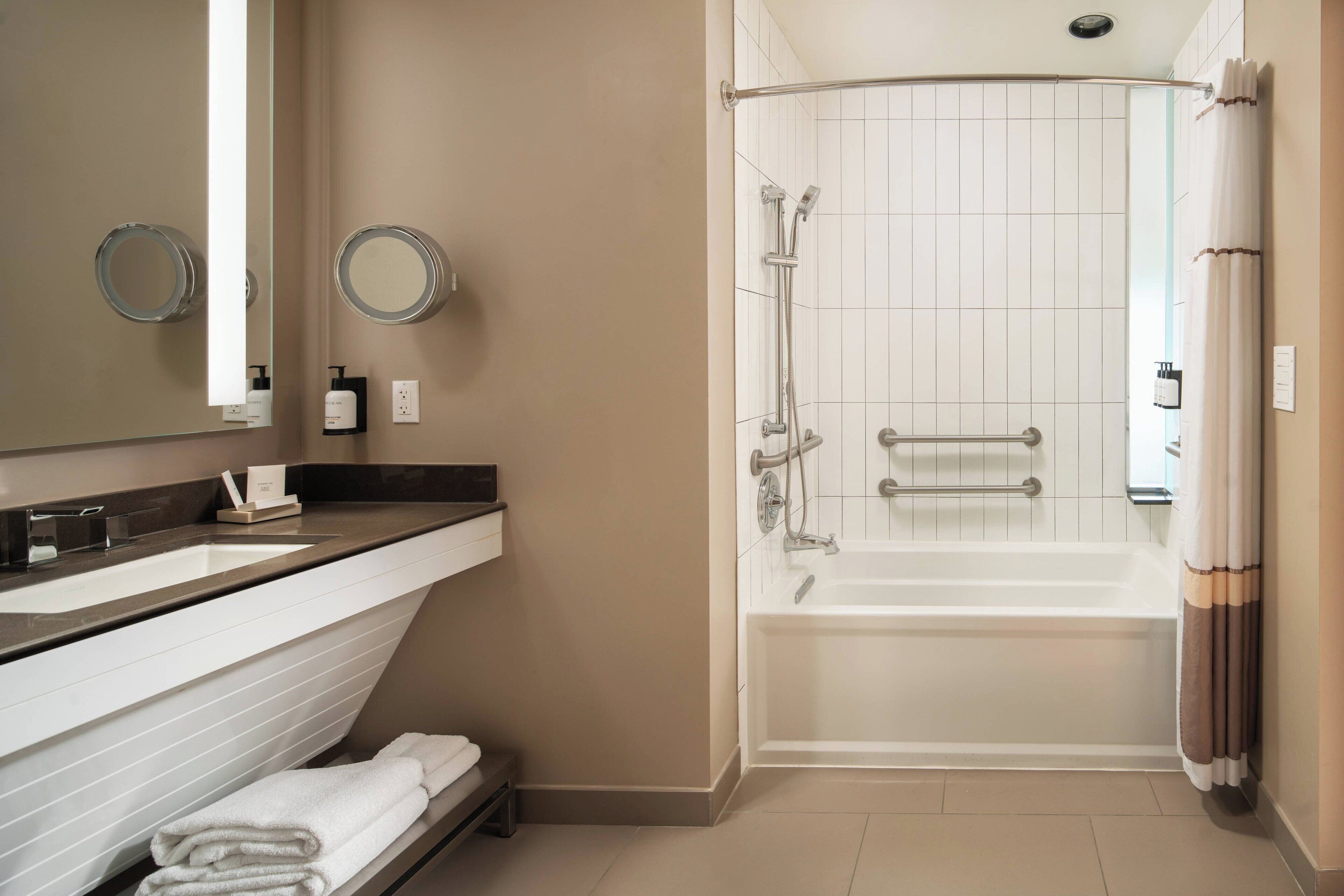 A bathroom with a double sink vanity, a large mirror, a shower with a glass door, and a bathtub.