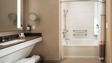 A bathroom with a double sink vanity, a large mirror, a shower with a glass door, and a bathtub.