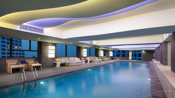 A modern indoor swimming pool with lounge seating and a view of the cityscape. - Ascott Raffles City Chengdu (Chengdu)