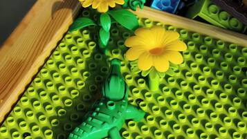 Ein LEGO-Set mit einem grünen Krokodil und gelben Blumen auf einer grünen Grundplatte.