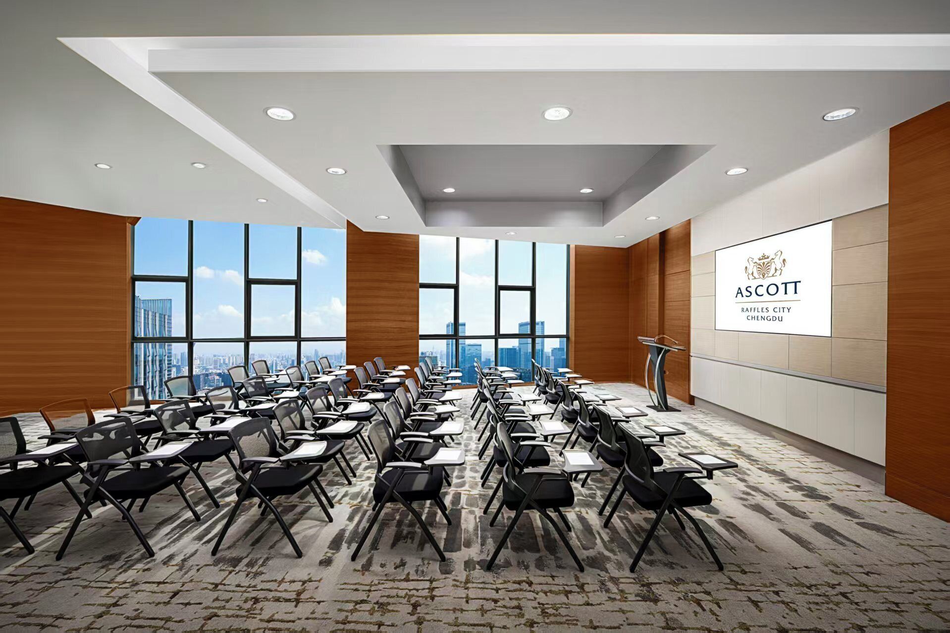 A conference room with rows of chairs, a podium, and a large window with a city view.