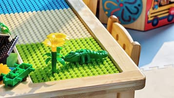 Una mesa de madera con un tapete de juego LEGO que muestra un dinosaurio y flores.