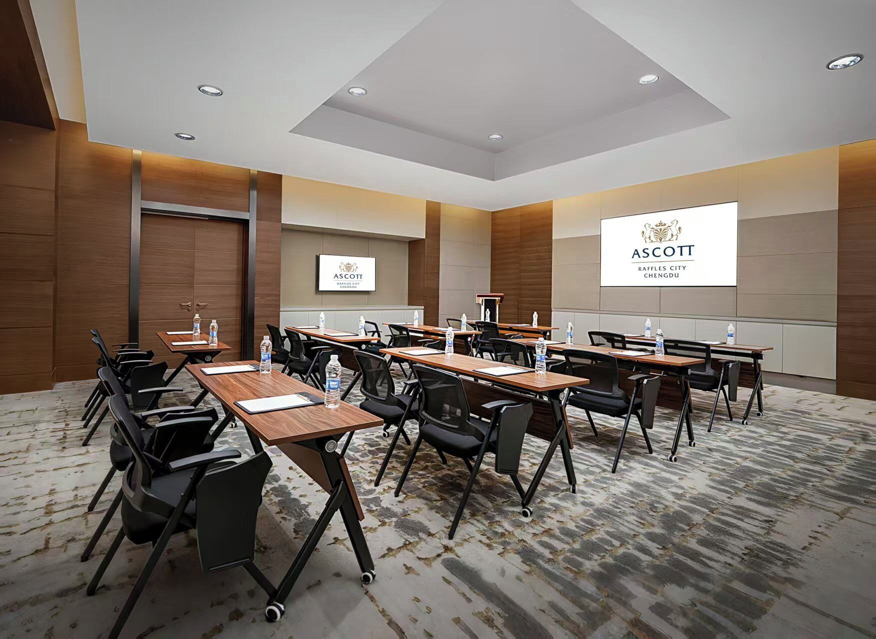 A conference room with multiple tables and chairs, equipped with water bottles and nameplates.