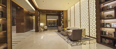 A modern lobby with a reception desk, seating area, and bookshelves.