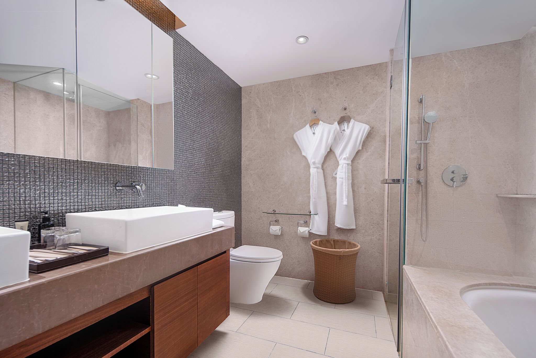 A modern bathroom with a large mirror, a white sink, a toilet, and a glass-enclosed shower.