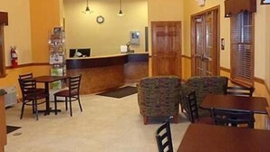 A hotel lobby with a reception desk, seating area, and a clock on the wall. - Budget Inn Williamsport (Williamsport)