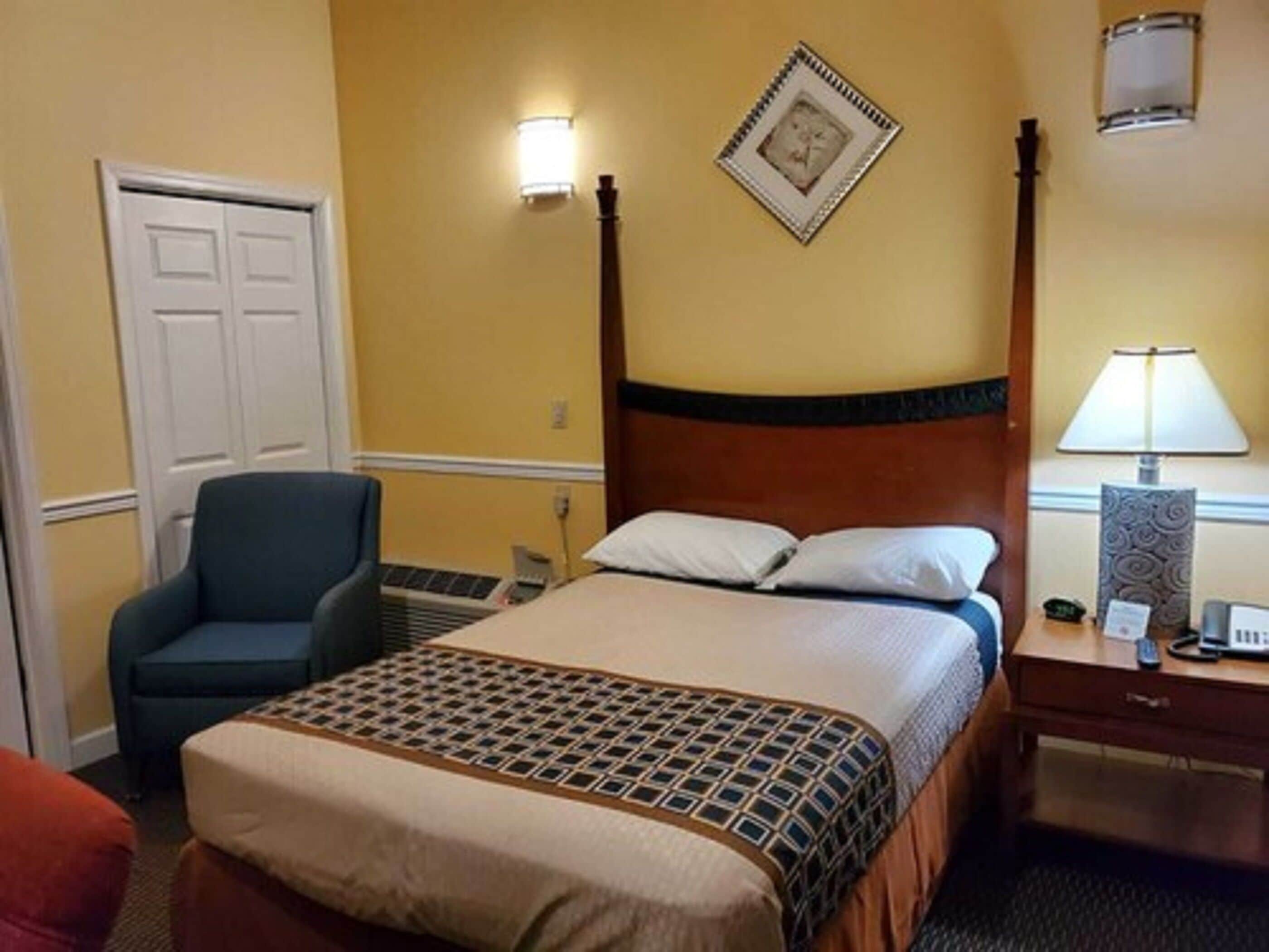 Een hotelkamer met een bed, een stoel, een bureau en een lamp.