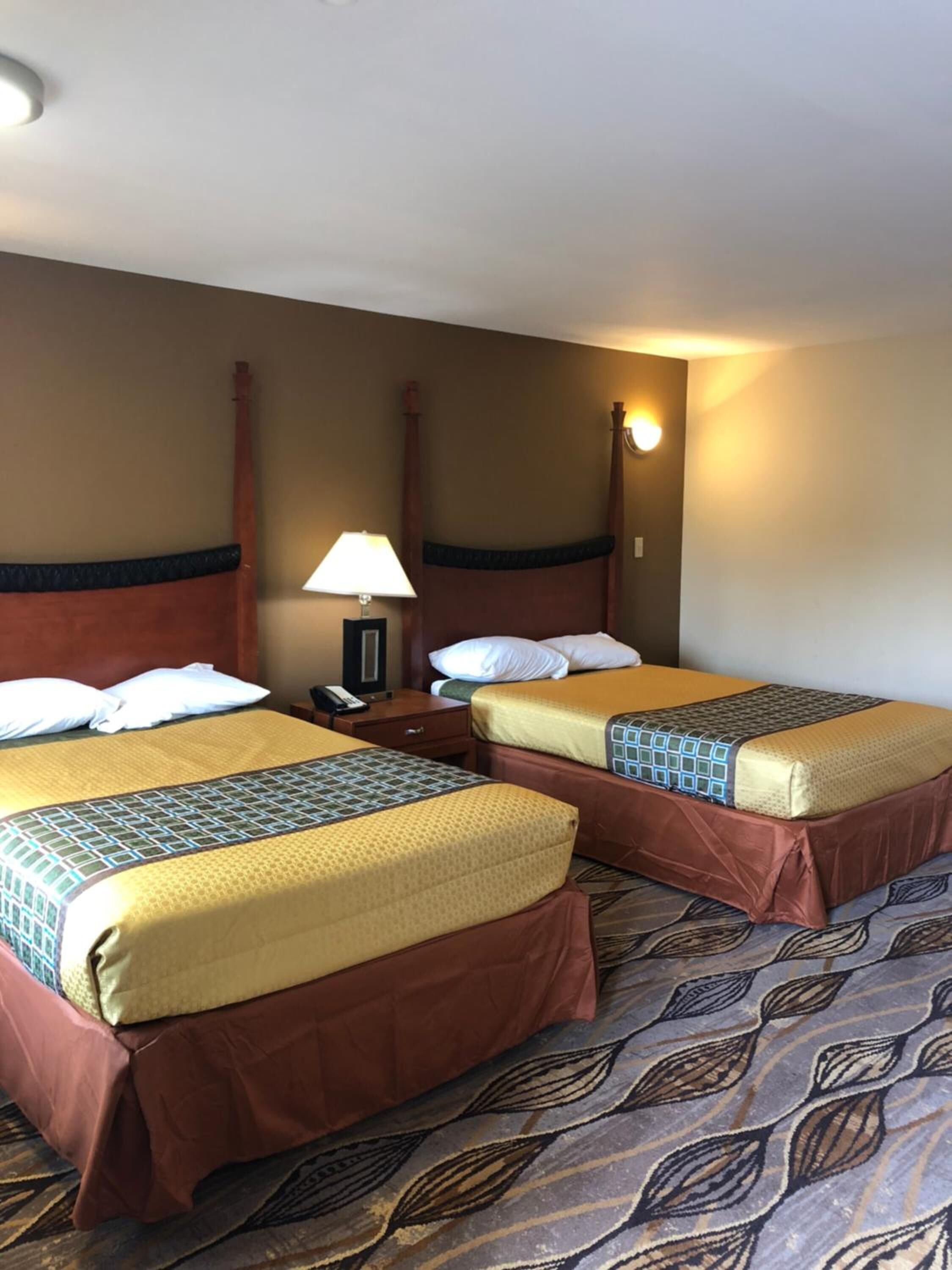 Een hotelkamer met twee bedden, elk voorzien van een hoofdeinde, nachtkastjes en lampen.